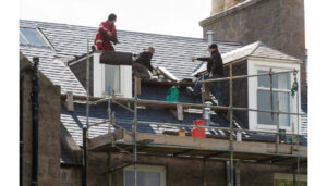 Men working at high on scaffolding fitting new slate roof
