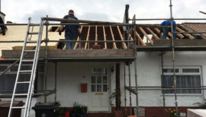 Workmen on scaffolding starting work on a new roof